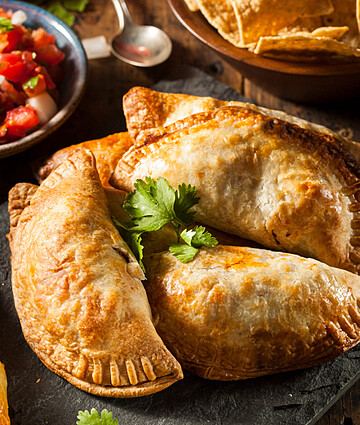 Savory chicken empanadas served with fresh salsa, perfect for appetizer spreads or casual dining.