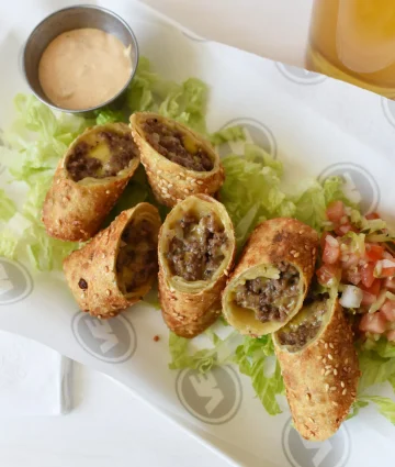 Golden crispy beef spring rolls with sesame seeds served on lettuce with fresh pico de gallo and creamy dipping sauce.