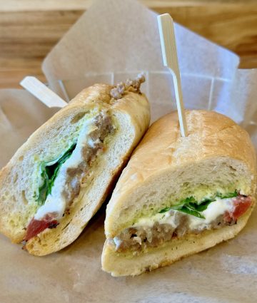 Professional-quality sandwich featuring pâté, fresh arugula, tomato, and creamy spread on artisan bread, ideal for foodservice and wholesale food suppliers.