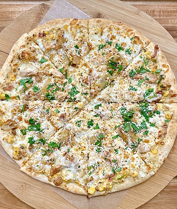 Savory chicken and corn pizza with golden crust, cheese, and fresh parsley, perfect for sharing.